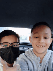 a boy wearing glasses and a black mask smiles for the camera