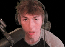 a young man wearing headphones looks at the camera with his mouth open