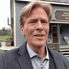 a man in a suit stands in front of a building that has a sign that says north shore mounted regiment