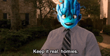 a man in a suit and tie with a blue monster on his face says keep it real homies