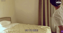 a man standing in front of a bed with the words go to bed