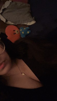 a woman laying on a bed with a stuffed animal and a necklace