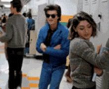 a group of people are standing in a hallway with lockers .