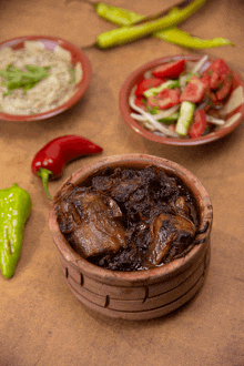 a bowl of stew sits on a table next to a plate of vegetables