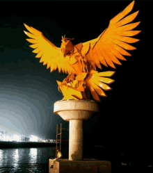 a man sits on a ladder next to a large yellow bird statue