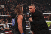 two men in a wrestling ring one of whom is wearing a black shirt with a picture of a woman on it