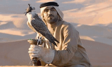 a man is holding a bird in his hands in the desert .