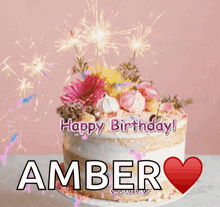 a birthday cake for amber with sparklers and flowers on top