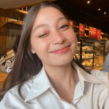 a woman in a white shirt is smiling in front of a starbucks display case