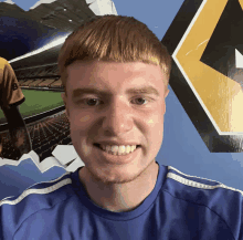 a young man wearing a blue shirt is smiling in front of a wall with a yellow arrow pointing to the right