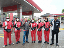 a group of people are posing for a photo in front of a pertamina gas station