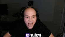 a bald man wearing headphones and a shirt that says vaidrah on it
