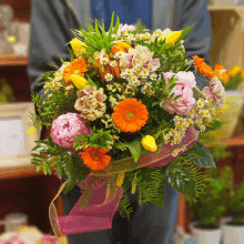 a person is holding a bouquet of flowers with a pink ribbon around it