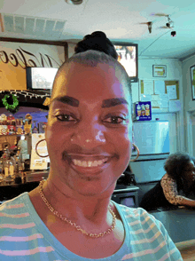 a woman in a striped shirt is smiling in front of a sign that says ' coca cola ' on it