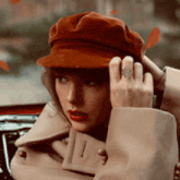 a woman wearing a red hat and a trench coat is sitting in a car .