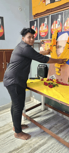 a man standing in front of a table with flowers and a picture of a man on it