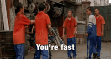 a group of boys are standing in front of a pile of ropes and a sign that says you 're fast on it