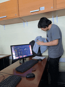 a man standing in front of a computer with a sign on the wall that says " no smoking "