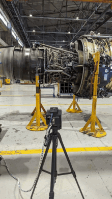 a jet engine is being worked on in a hangar with a camera on a tripod in front of it