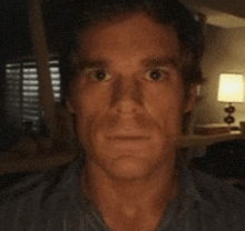 a man is taking a selfie in a dark room with a lamp in the background .