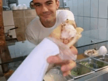 a man in a white shirt is holding a sandwich in his hand .