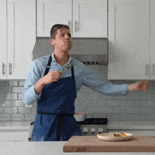 a man in an apron is dancing in a kitchen with a plate of food on a cutting board that says boys