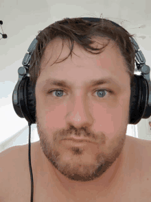 a man wearing headphones looks at the camera with a serious look on his face