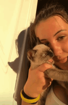 a woman with a yellow wristband holds a cat in her arms