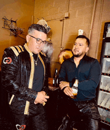 two men are standing in front of a corona fridge