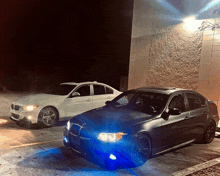 two cars are parked in front of a building at night