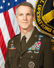 a man in a military uniform is standing in front of an american flag and a military operations seal