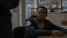 a man sits at a desk with a patch on his sweatshirt that says chicago