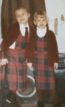 two girls wearing plaid school uniforms pose for a picture