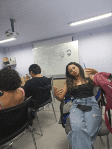 a woman sits in a chair in front of a white board with drawings on it including a man and a woman