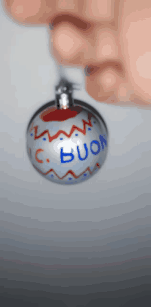 a person holding a christmas ornament that says buon on it