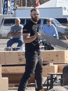 a man with a beard is holding a large saw in front of a sign that says fina