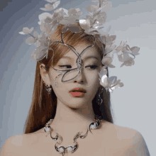 a woman wearing a necklace and a crown of white flowers on her head