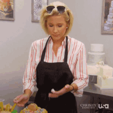 a woman in a striped shirt and apron is standing in front of a cake with a usa logo on the bottom