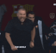 a group of men are standing in front of a sign that says " fcb world "
