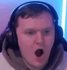 a man wearing headphones is making a funny face while playing a video game .