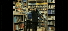 a man in a suit is holding a cellphone in a bookstore