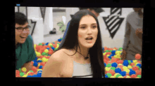 a woman is standing in a ball pit with a man behind her