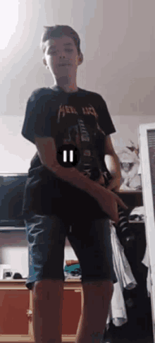 a young boy wearing a metallica shirt is standing in front of a television