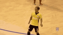 a soccer player in a yellow jersey and black shorts is dancing on a court .