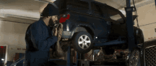 a man is working on a car in a garage that has a sign that says no smoking