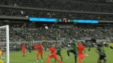 a soccer game is being played in front of a crowd with a scoreboard that says ' coca cola ' on it