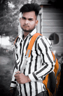 a man in a black and white striped shirt is carrying a backpack