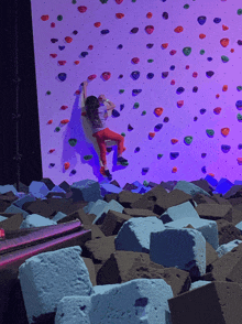 a little girl is climbing a climbing wall with purple lights behind her