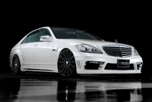 a white mercedes benz with black rims is parked in a dark garage