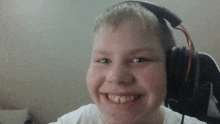 a young boy wearing headphones looks at the camera and smiles